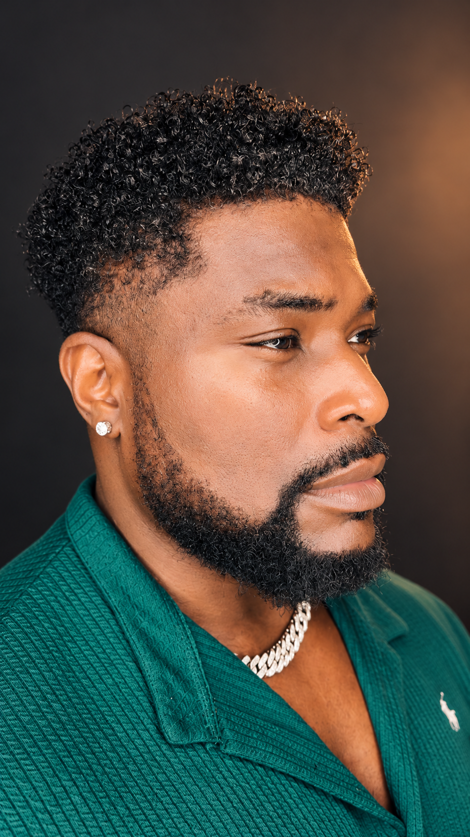 Professional portrait of Allen in an emerald shirt against a warm charcoal studio background